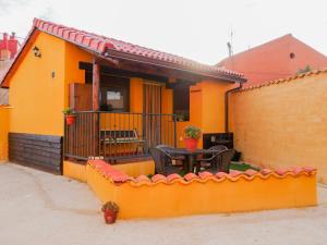 a yellow house with a table and a fence at Apartamentos Rurales El Casarejo in Cantalojas