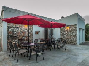 eine Terrasse mit Tischen, Stühlen und roten Sonnenschirmen in der Unterkunft Silba Otium in Silba