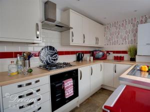 a kitchen with white cabinets and a stove top oven at Sunny Days in Weymouth