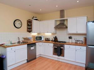 a kitchen with white cabinets and a clock on the wall at Aeolus House in Dartmouth