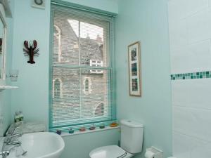 a bathroom with a toilet and a sink and a window at Aeolus House in Dartmouth