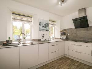 a kitchen with white cabinets and a sink at Faodail Glenlia in Foyers