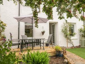 a patio with a table and chairs and an umbrella at Faodail Glenlia in Foyers