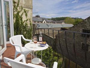 a table with two chairs and a bottle of wine on a balcony at Chapel House in Dartmouth