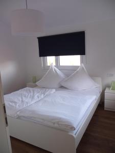 uma cama branca com almofadas brancas e uma janela em Ferienwohnung Sauer em Blaichach