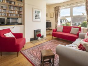 een woonkamer met twee rode banken en een open haard bij Camar in Salcombe