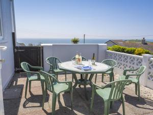 een tafel met stoelen en flessen wijn op een balkon bij Seaspray Bigbury-on-Sea in Bigbury on Sea