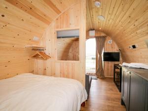 a bedroom with a large bed in a wooden room at Garraidh Ghorm Pod in Portree