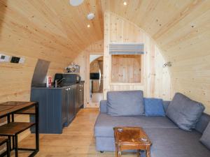 a living room with a blue couch and a kitchen at Garraidh Ghorm Pod in Portree