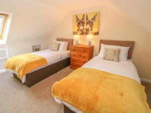 a bedroom with two beds and a dresser at Pottery Cottage in Kilgetty