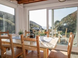 a dining room with a table and chairs and large windows at Little Ruffo in Tintagel