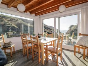 a dining room with a table and chairs and large windows at Little Ruffo in Tintagel