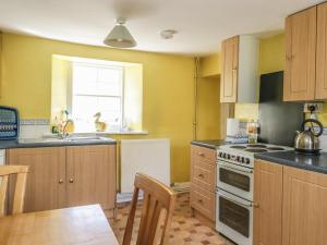 a kitchen with wooden cabinets and a stove top oven at Balmeanoch in Lochearnhead