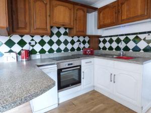 a kitchen with white cabinets and black and white tiles at The Old Clockmakers in Norwich