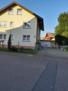 ein weißes Haus mit einem Zaun davor in der Unterkunft Ferienwohnung Toska in Pfaffenweiler