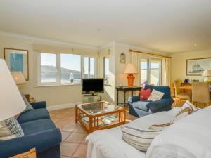 uma sala de estar com um sofá azul e uma televisão em 6 Burgh Island Causeway em Bigbury on Sea
