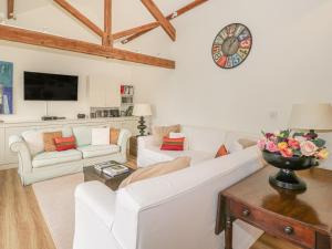 a living room with white furniture and a clock on the wall at The Cider Barn in Warminster