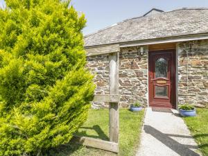 a stone cottage with a wooden door and a pine tree at Garras Barn in Truro