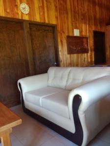 um sofá branco num quarto com um relógio na parede em Cabañas Tornagaleones Villarrica em Villarrica