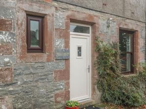 a white door on a stone building with windows at Hillcrest in Newton Stewart