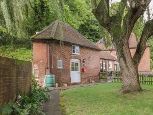 ein Backsteinhaus mit einer weißen Tür und einem Baum in der Unterkunft Weir Cottage in Maidstone