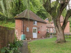 a brick house with a white door and a tree at Weir Cottage in Maidstone