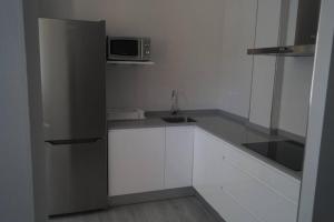 eine Küche mit weißen Schränken und einer Mikrowelle in der Unterkunft Apartamentos los Acantilados Nº 1 Cobreces in Cóbreces