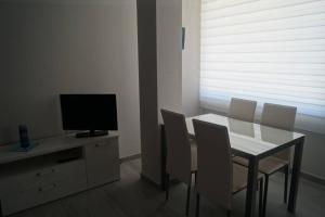 una sala da pranzo con tavolo, sedie e TV di Apartamentos los Acantilados Nº 1 Cobreces a Cóbreces