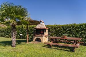 a picnic table and a brick oven next to a table and a palm tree at Villa Katerina in Siviri