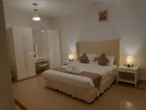 una camera da letto con un grande letto con due tavoli e due lampade di Muscat Oasis Residences a Mascate