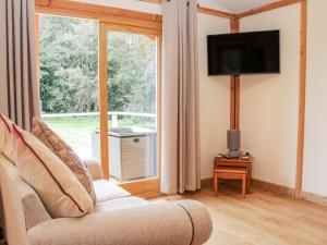 a living room with a couch and a large window at Moorhen Lodge in Oswestry