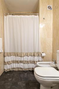 a bathroom with a toilet and a shower curtain at Samaná Departamentos in El Bolsón