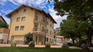 Un grand bâtiment jaune avec balcon est disponible. dans l'établissement Albergo San Giorgio, à Baselga di Pinè