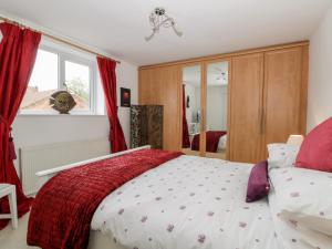 a bedroom with a bed with red curtains and a window at Little Daisy Cottage in Hornsea