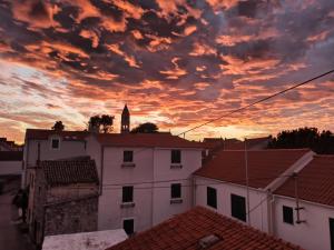 um pôr-do-sol sobre os telhados de edifícios com uma igreja em Apartments Vrime em Biograd na Moru