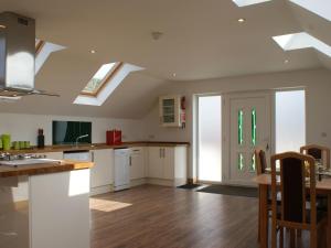 a kitchen with white cabinets and a ceiling with skylights at Seagulls Perch in Mawgan Porth