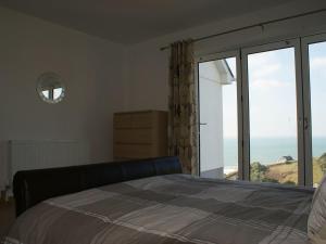a bedroom with a bed and a view of the ocean at Seagulls Perch in Mawgan Porth