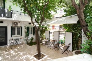 アテネにあるAthens Green Apartmentsの建物の前に木と椅子付きのパティオ