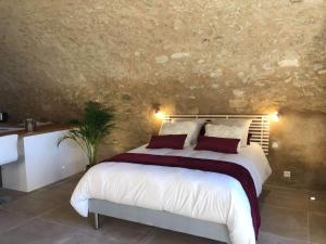 a bedroom with a large white bed and a stone wall at Paradise Love In Provence - loft en pierres - spa privatif in Reillanne