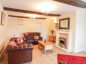 a living room with leather furniture and a fireplace at Stone Farm Cottage in Sheffield