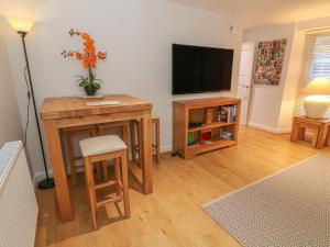 a living room with a television and a table and stool at Flat 2 Galloway House in Kendal