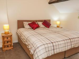 a bedroom with a bed with two red pillows at Stone Farm Cottage in Sheffield