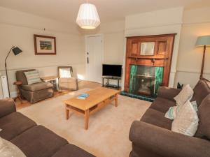 a living room with a couch and a table and a fireplace at Savernake in Thurlestone