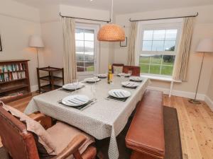 a dining room with a table and chairs and windows at Savernake in Thurlestone