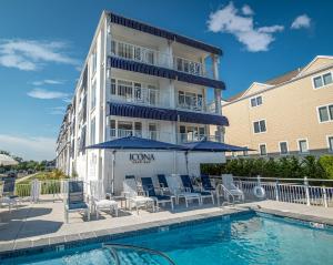 um hotel com uma piscina com cadeiras e guarda-sóis em ICONA Cape May em Cape May