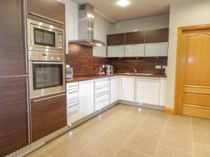 una cocina con armarios blancos y electrodomésticos de acero inoxidable en Apartment 1 St Mary's Church, en Moffat