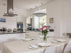- une cuisine blanche avec une table et des fleurs dans l'établissement The Upper Deck, à Penzance