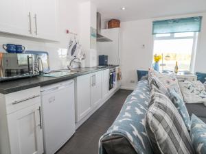 a kitchen with white cabinets and a long couch at Bracken Barn Cottage in Morpeth +14 photos