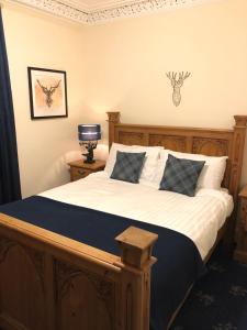 a bedroom with a wooden bed with white sheets and pillows at Ness House in Inverness