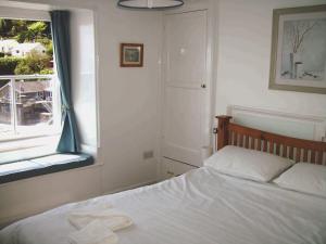 a bedroom with a white bed and a window at Balcony Cottage in Cawsand